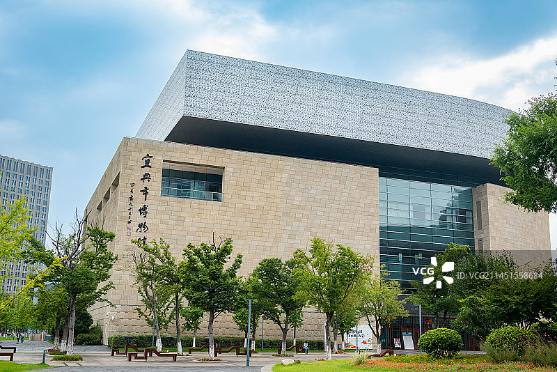 蓝天白云下的宜兴市博物馆建筑外观掩映在郁郁葱葱的树从中图片素材