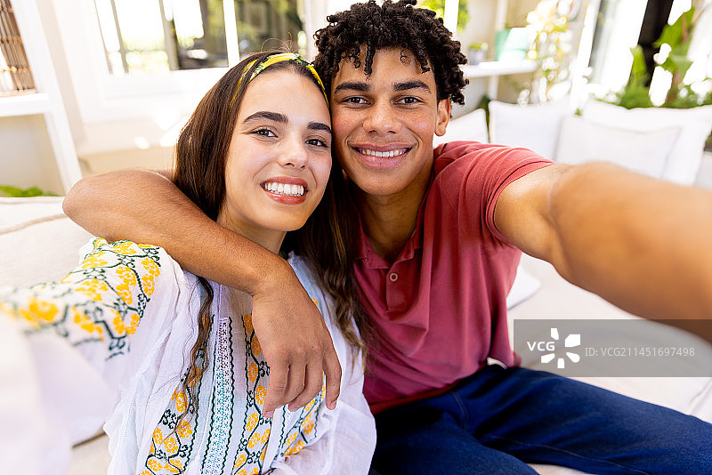 幸福的混血情侣在客厅沙发上自拍图片素材