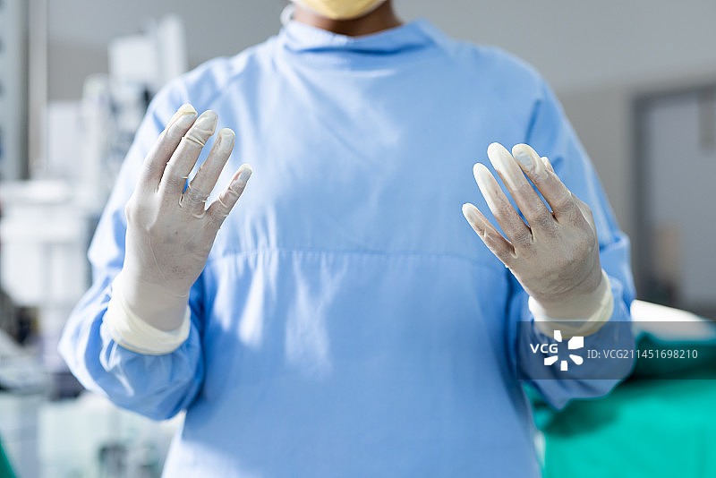 手术室里穿着手术服和手套的外科医生身体中部图片素材