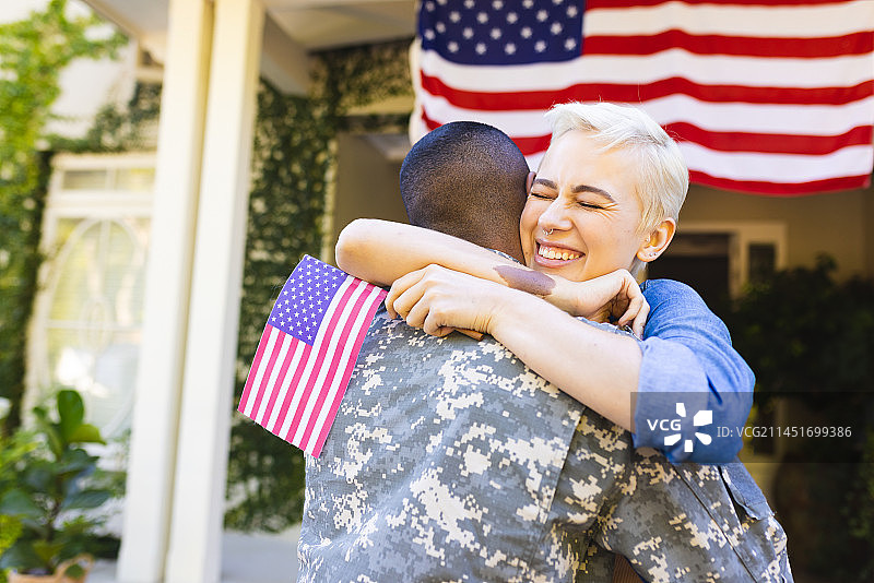 快乐的白人女性和非裔美国男兵在屋外拥抱图片素材