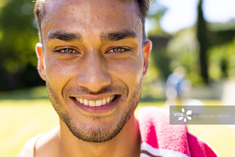 花园里肩上搭着毛巾、看着镜头微笑的快乐混血男人像图片素材