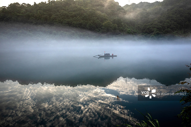 湖南郴州市资兴小东江，渔民在晨雾中划船撒网捕鱼图片素材