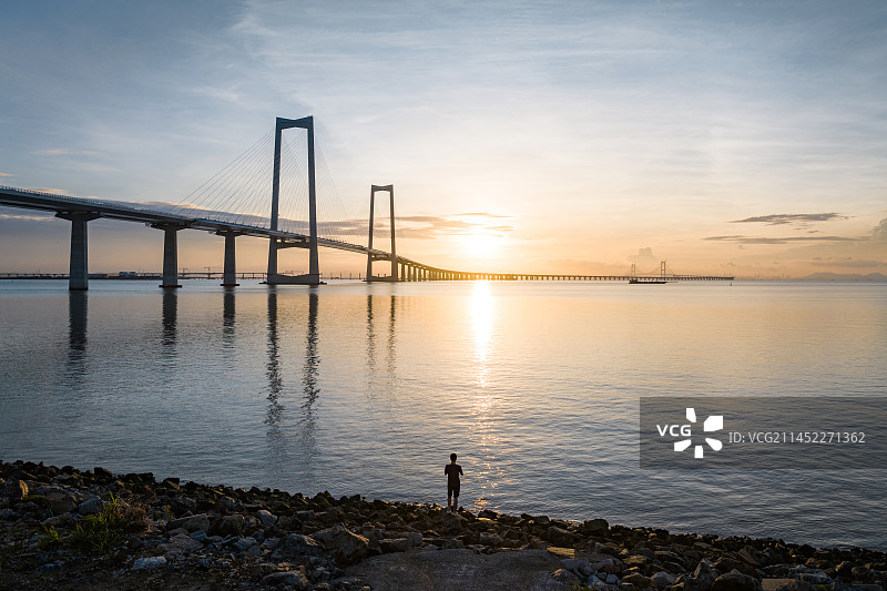 一年轻人在深中通过海边观看日出图片素材