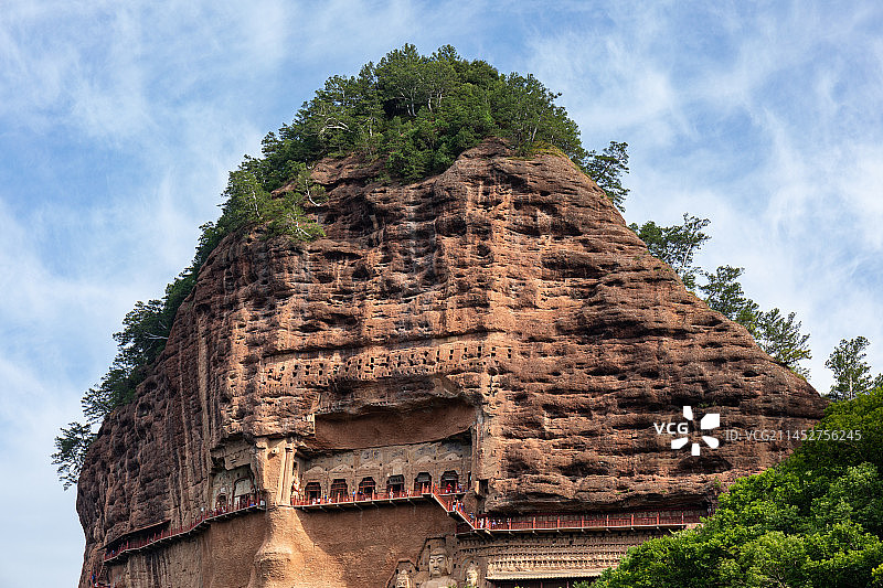 甘肃天水麦积山石窟建在石头山上的佛教造像窟夏天覆盖着绿色树木的麦积山全貌图片素材