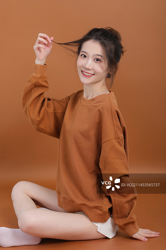 橙色背景下微笑的年轻女子肖像图片素材