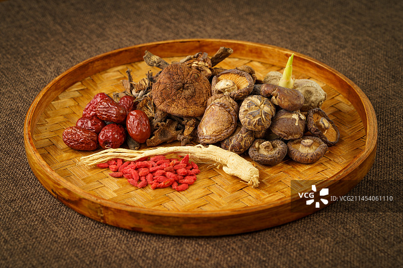 单色背景下放在竹编盘内的多种山珍干货图片素材