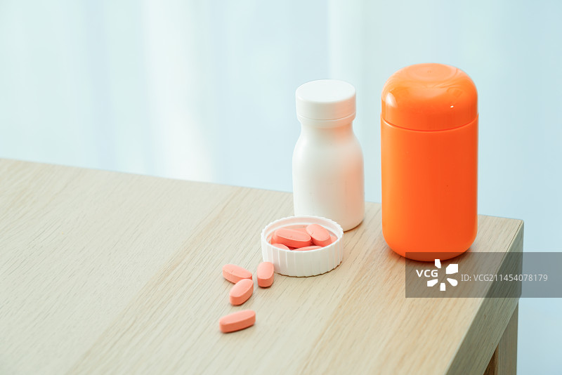 橘色的药片和药瓶子放在桌面上图片素材