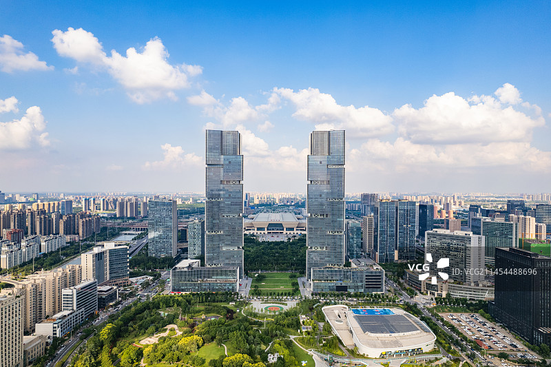 蓝天白云下的河南郑州地标建筑郑东绿地中心双子塔与郑东新区市民体育公园高视角航拍城市风光全景图片素材