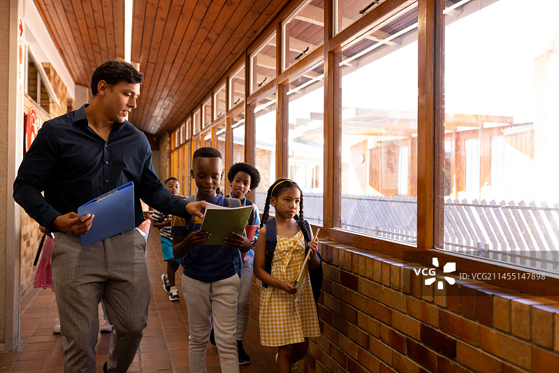 小学走廊里，男老师和孩子们走在一起图片素材