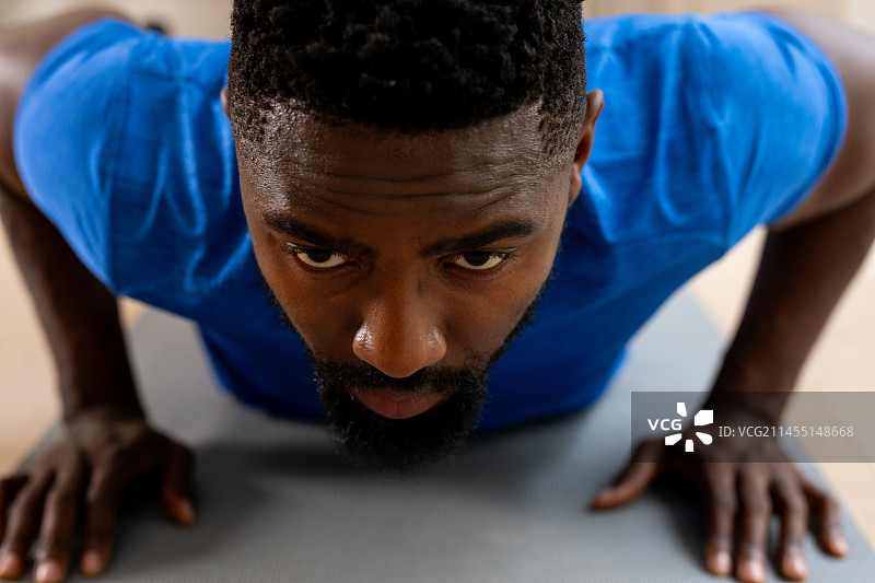 非裔美国男子在家里的垫子上锻炼图片素材