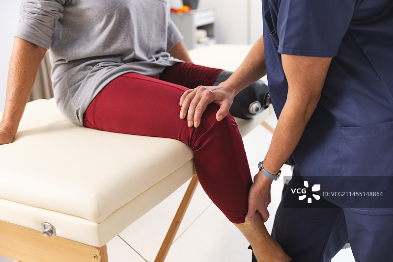 理疗师和使用假肢的老年妇女在医院做伸展运动图片素材