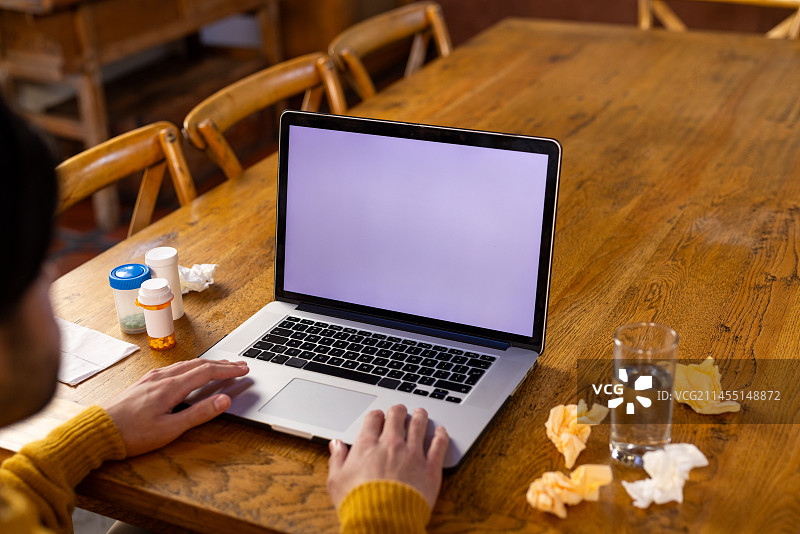 印度男子在桌子上放着药物，使用笔记本电脑进行视频通话，屏幕上有复制空间图片素材