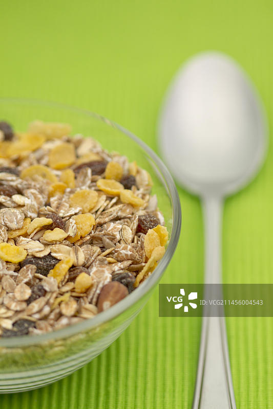 盛有麦片和勺子的玻璃碗（绿色桌布上）图片素材