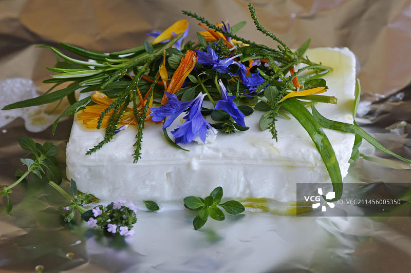烤山羊奶酪，烤奶酪，无肉烧烤，烹饪香草，顶部配万寿菊花，矢车菊花，龙蒿，迷迭香，百里香，橄榄油图片素材