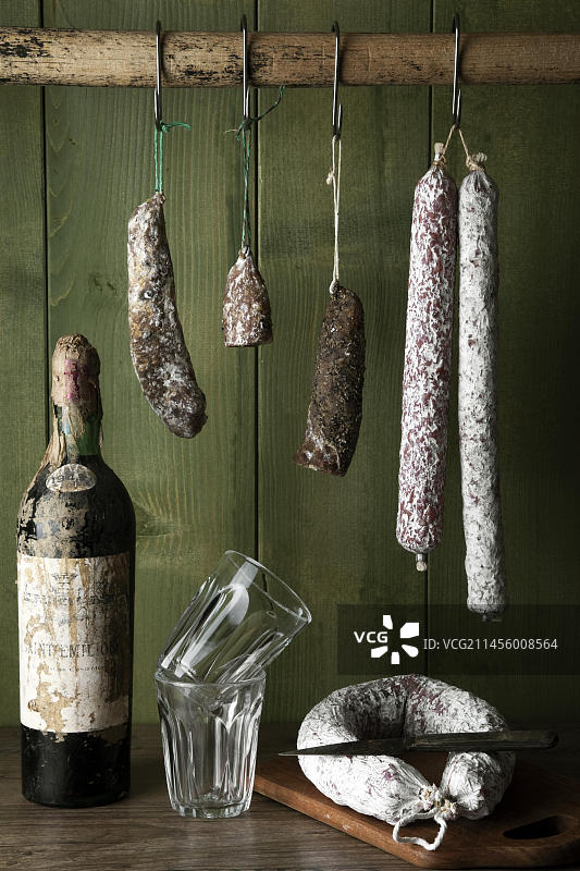 挂在绿色木墙前的各种萨拉米香肠图片素材