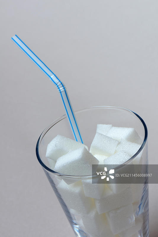 带吸管的玻璃杯中的糖块，白砂糖，甜菜糖图片素材