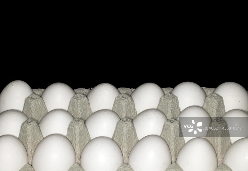 蛋盒中带白色外壳的18个鸡蛋，黑色背景下的食物摄影图片素材