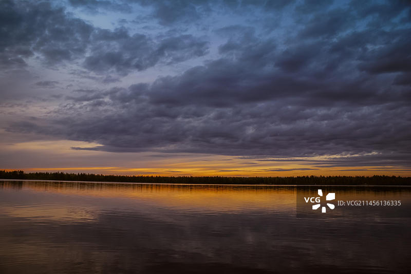 芬兰拉努阿：湖上多云的天空和远处的黑暗森林图片素材