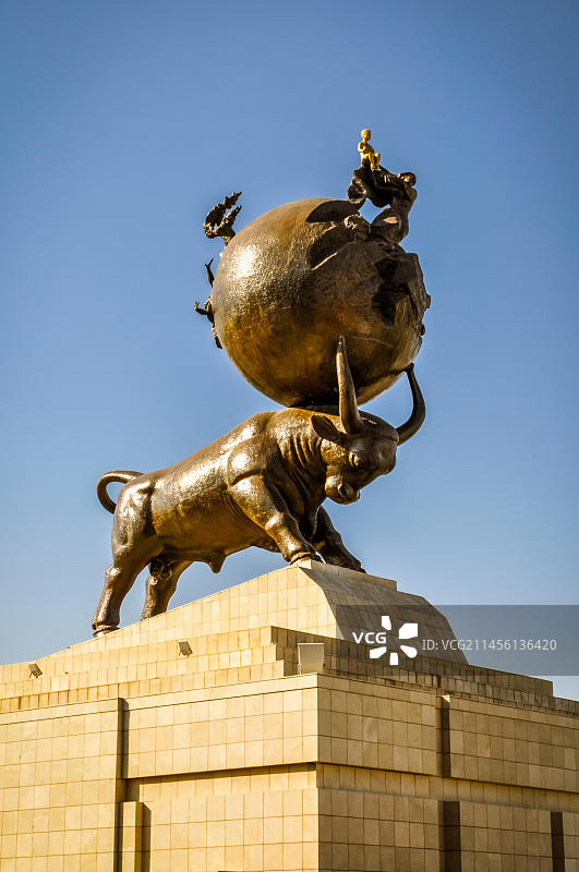 土库曼斯坦阿什哈巴德，公牛雕塑的角上顶着一个大球，立在石质底座上图片素材