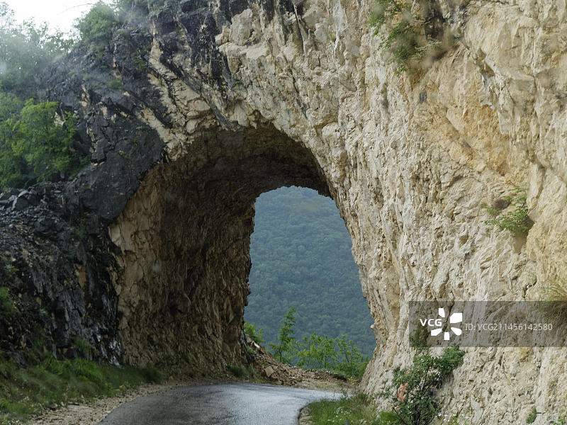 在杜密特山的公路上穿过岩石。周围的杜尔米特国家公园被联合国教科文组织列为世界遗产。Pluzine，黑山，东南欧，欧洲图片素材