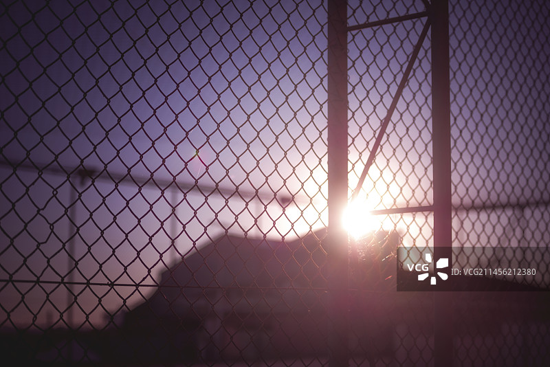 铁丝网后建筑物的轮廓剪影图片素材