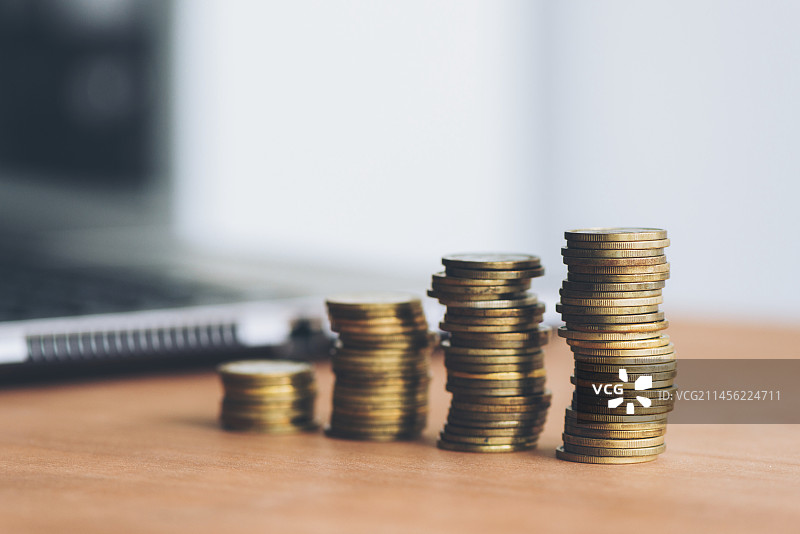 堆叠的硬币和笔记本电脑图片素材