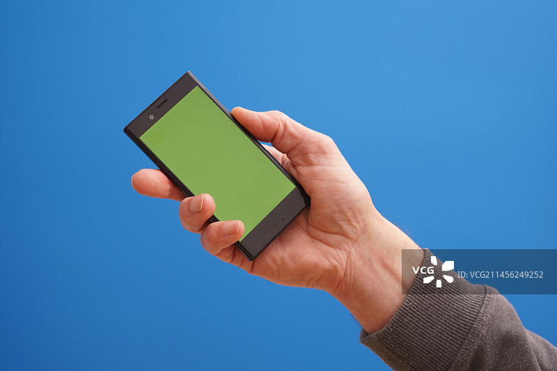 手持带绿屏手机的人图片素材