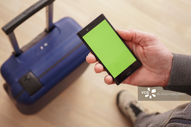 手持绿屏手机和行李箱的人图片素材