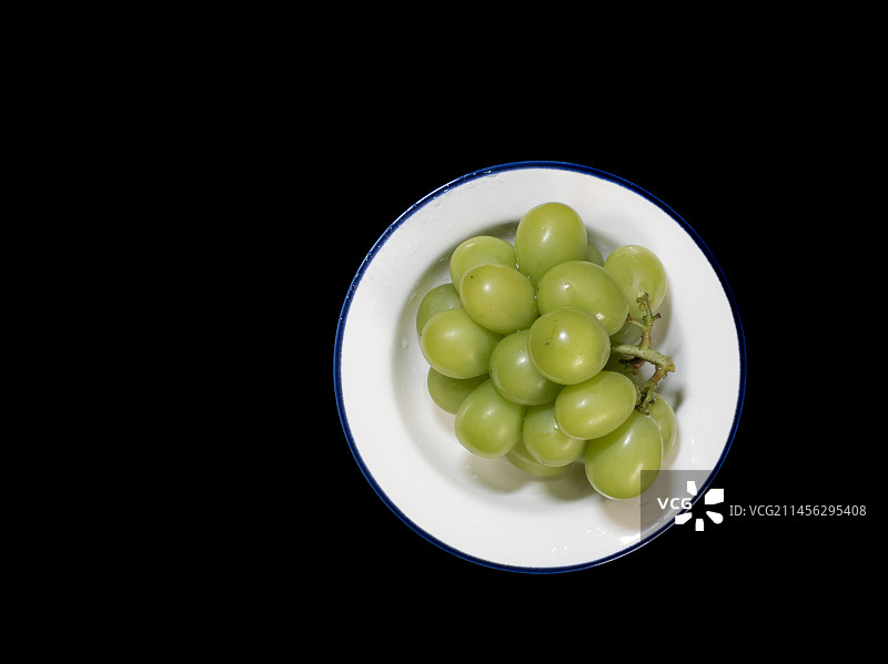 黑色背景下装在碗里的绿葡萄图片素材