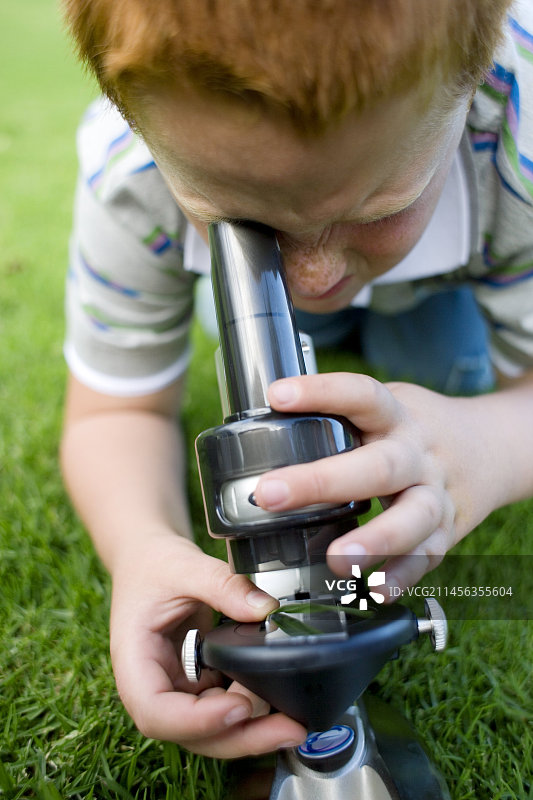 男孩使用光学显微镜图片素材
