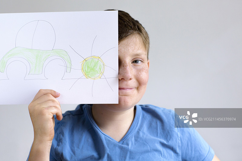 男孩手拿汽车和太阳的画作图片素材