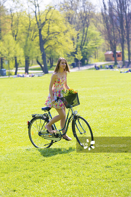 骑着载有鲜花篮子自行车的女人图片素材