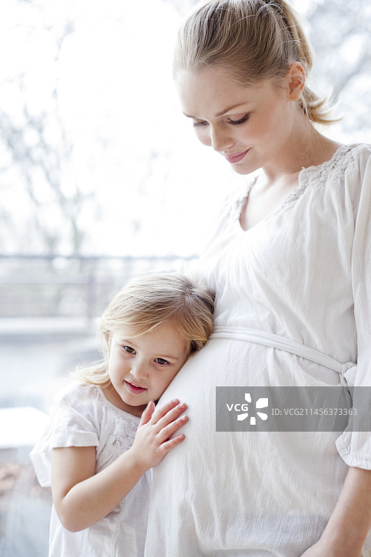 和怀孕的妈妈在一起的女孩图片素材