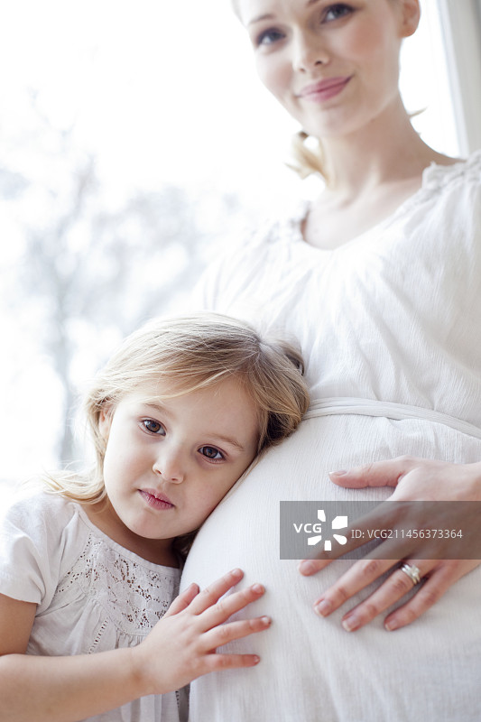 和怀孕的妈妈在一起的女孩图片素材