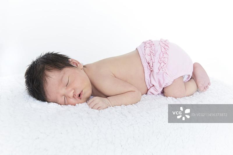 穿着粉色尿布的睡着的新生女婴图片素材