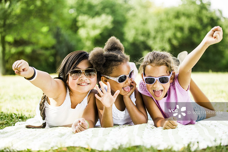 女孩们躺在公园的毯子上图片素材