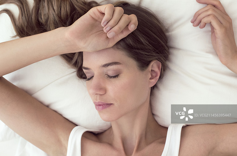 闭着眼睛躺在床上的年轻女人图片素材