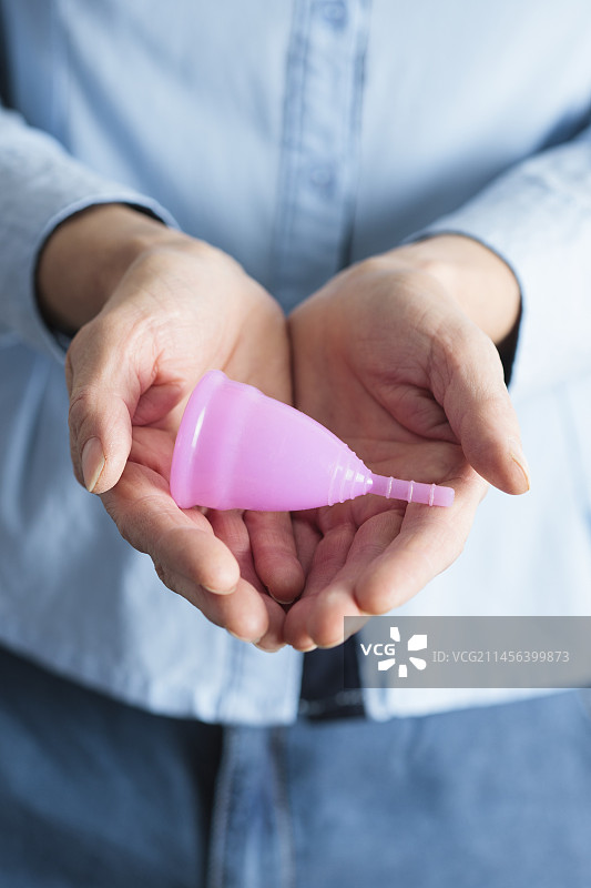 手持粉色月经杯特写图片素材