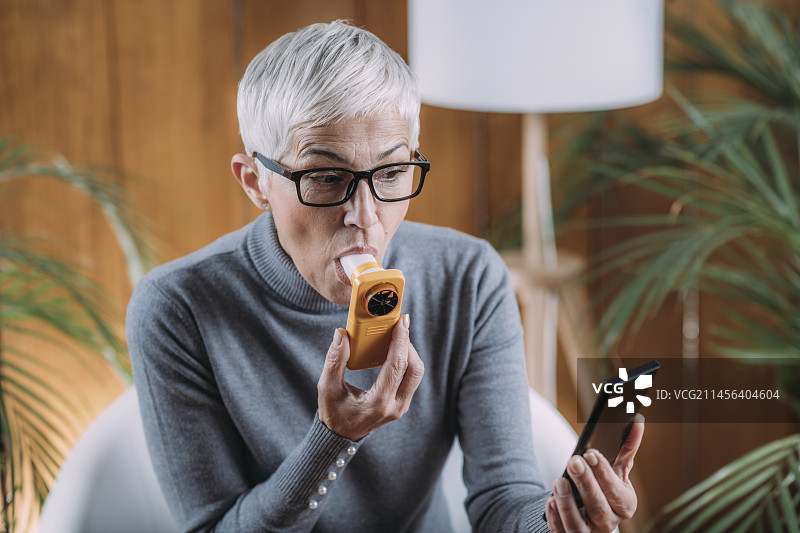 年长的女人在家使用肺活量计图片素材