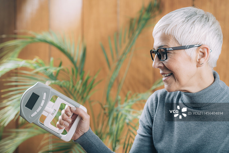 老年妇女使用数字握力计图片素材