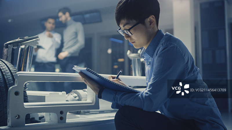 坐在电动汽车旁的汽车设计师图片素材