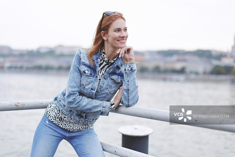 微笑的女人在河岸边看向远方图片素材