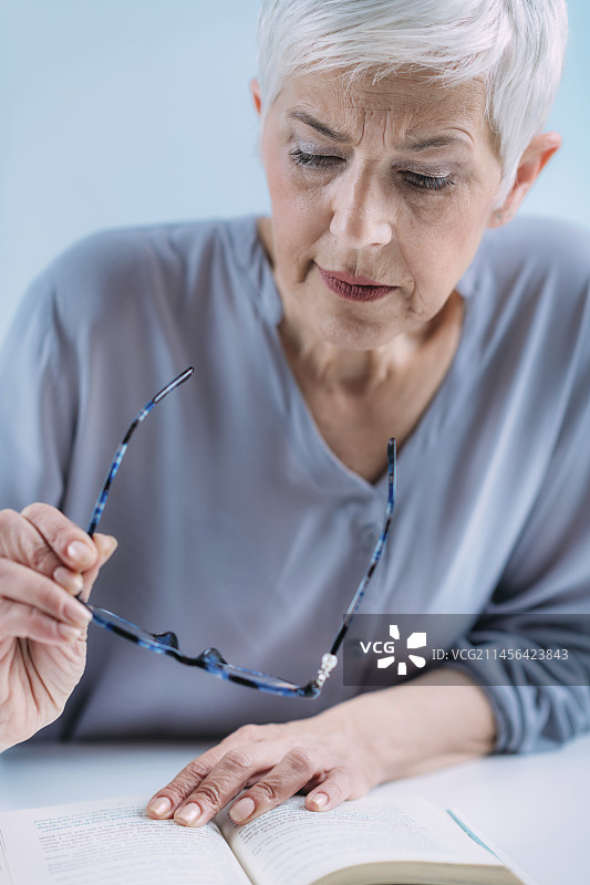 年长的女人拿着老花镜读书图片素材