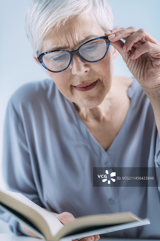 戴着眼镜读书的年长女性图片素材