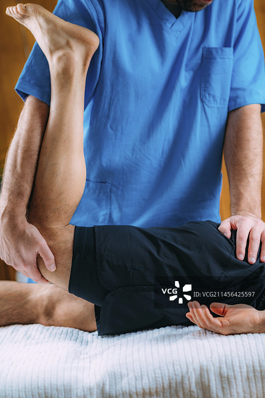 理疗师为受伤的男运动员按摩腿部图片素材