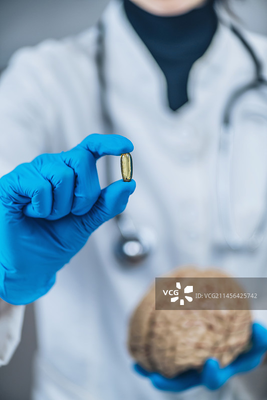 女医生手持大脑模型和安慰剂药丸图片素材