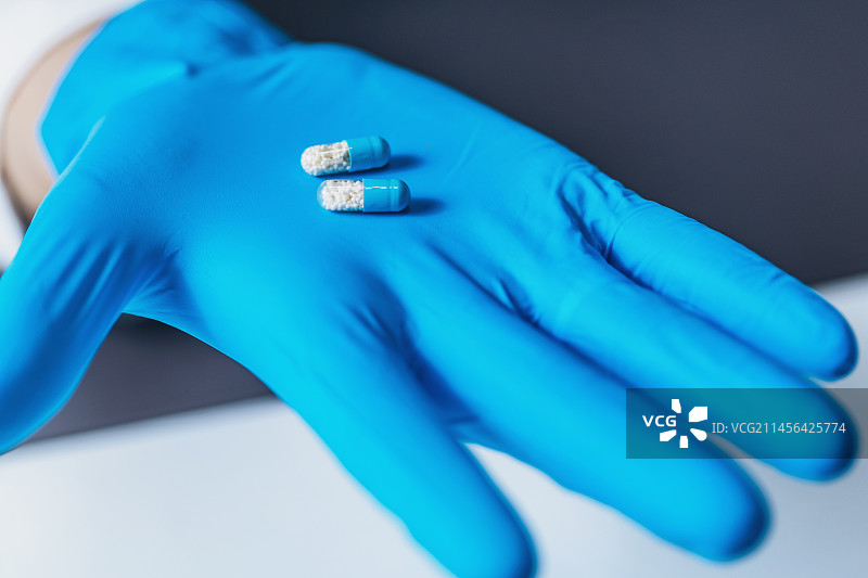 戴手套的手拿着真药和安慰剂药丸图片素材