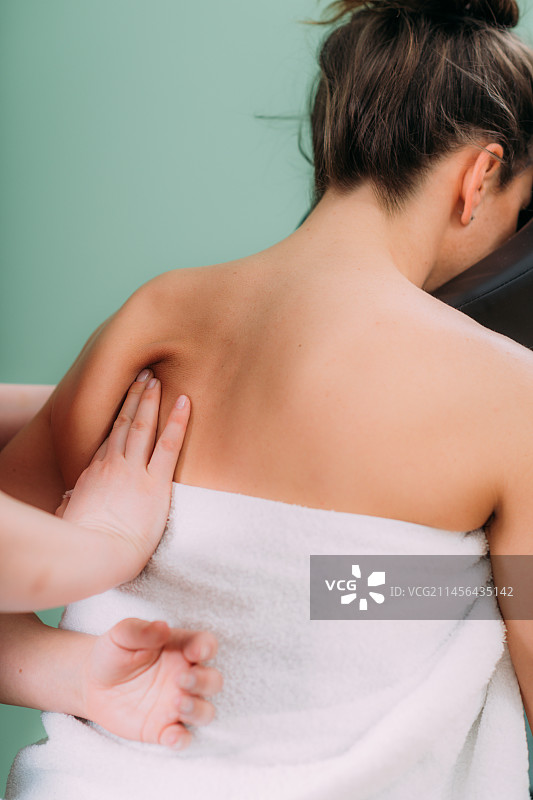 椅子按摩：按摩治疗师为女士进行背部按摩图片素材