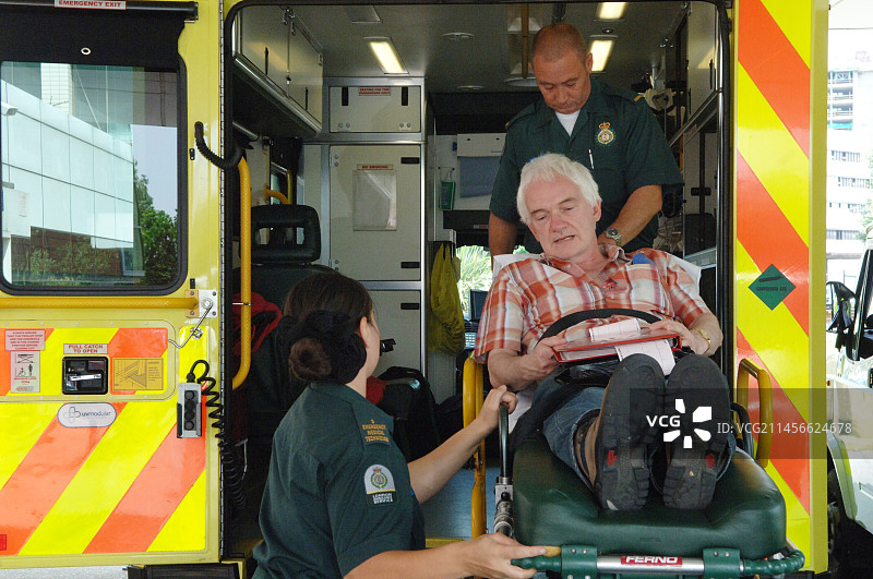 护理人员将一位老年患者抬上救护车图片素材
