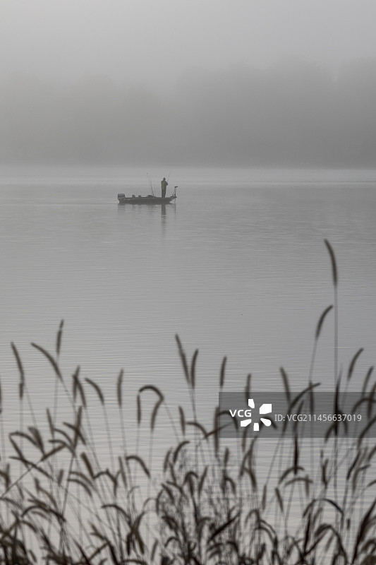 雾气笼罩的湖面上的渔夫图片素材